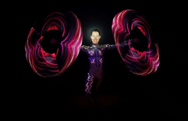 Inge Evers in een spiegelpak spint met 2 visual poi's, deze poi's laten mooie patronen zien.